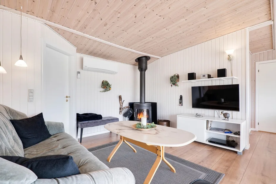 Una sala de estar luminosa con sofá, mesa de centro y estufa de leña.