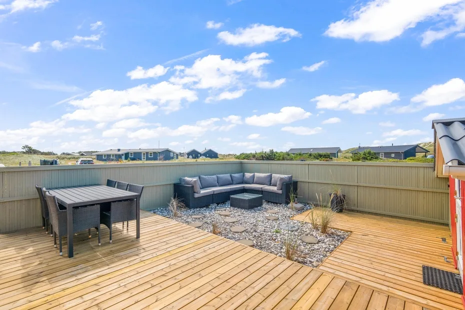 Una terraza exterior con una mesa y asientos alrededor de una zona de grava.