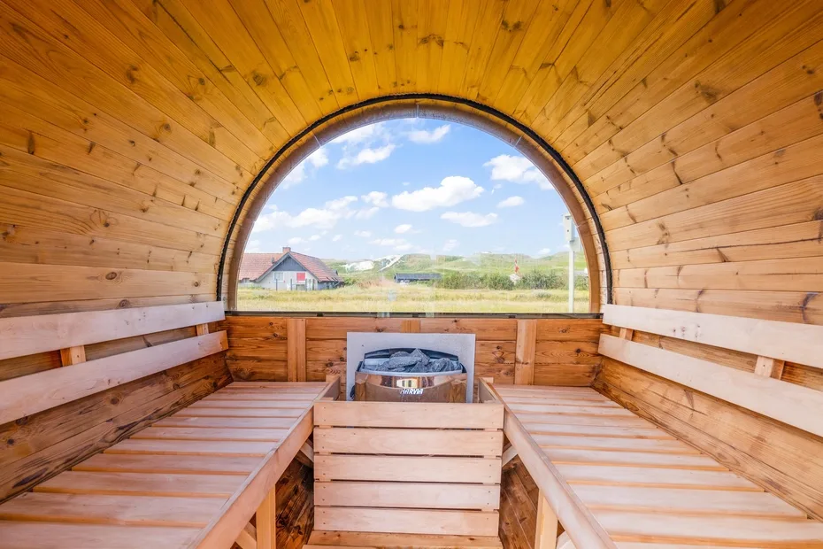 Una sauna de madera tiene asientos escalonados alrededor de una gran ventana arqueada.