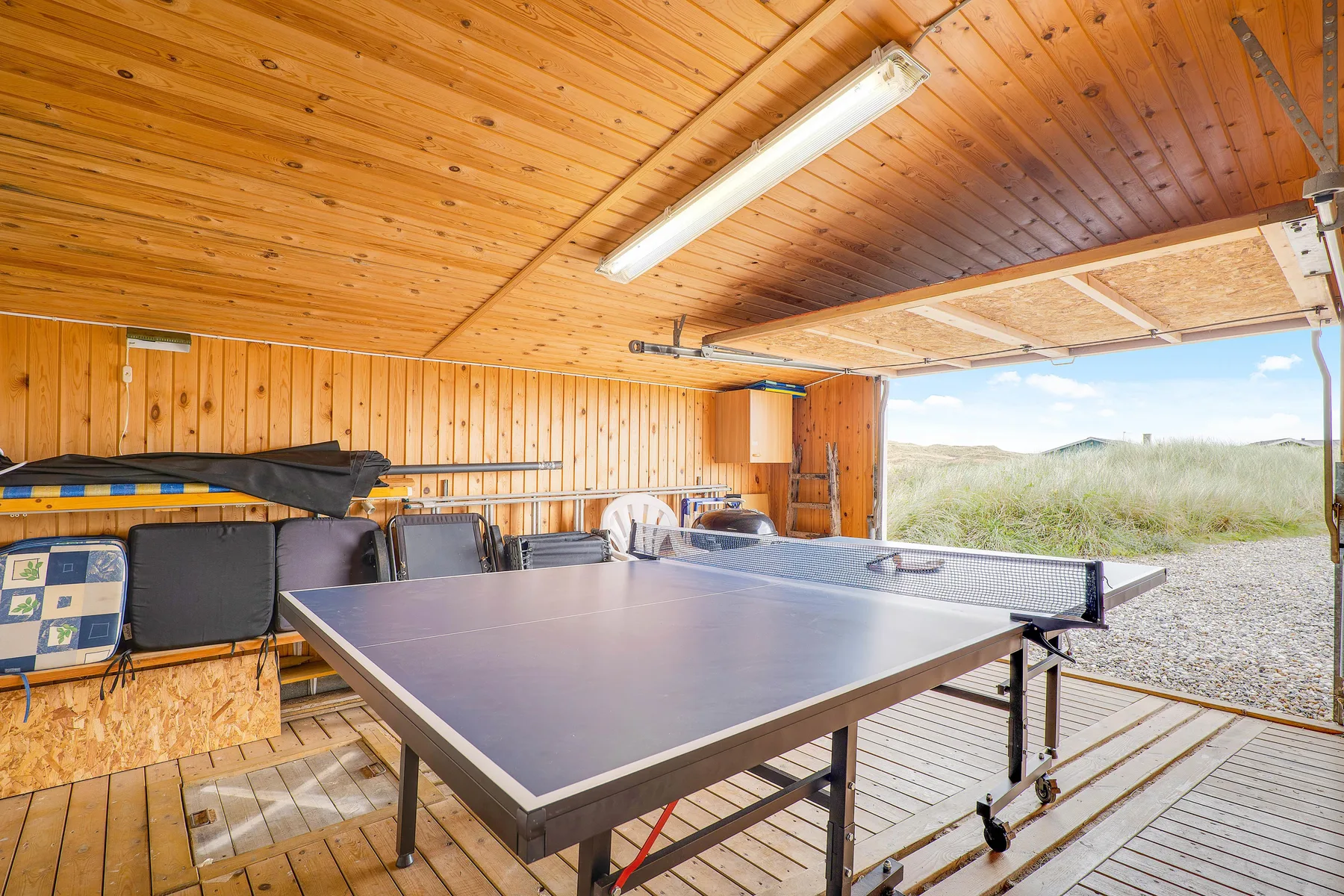 Una zona recreativa cubierta cuenta con una mesa de ping-pong y asientos junto a una vista abierta de las dunas.