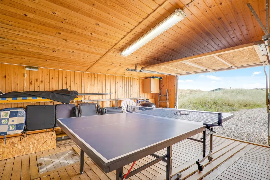 Una zona recreativa cubierta de madera con una mesa de ping-pong y vistas abiertas al paisaje.