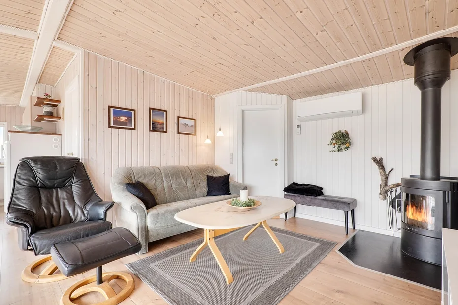 Una sala luminosa con asientos, una mesa de centro y techo revestido de madera.