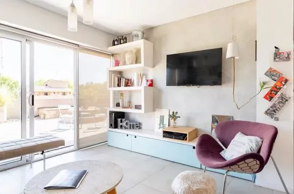 Una sala luminosa con puertas corredizas de vidrio y un televisor en la pared.