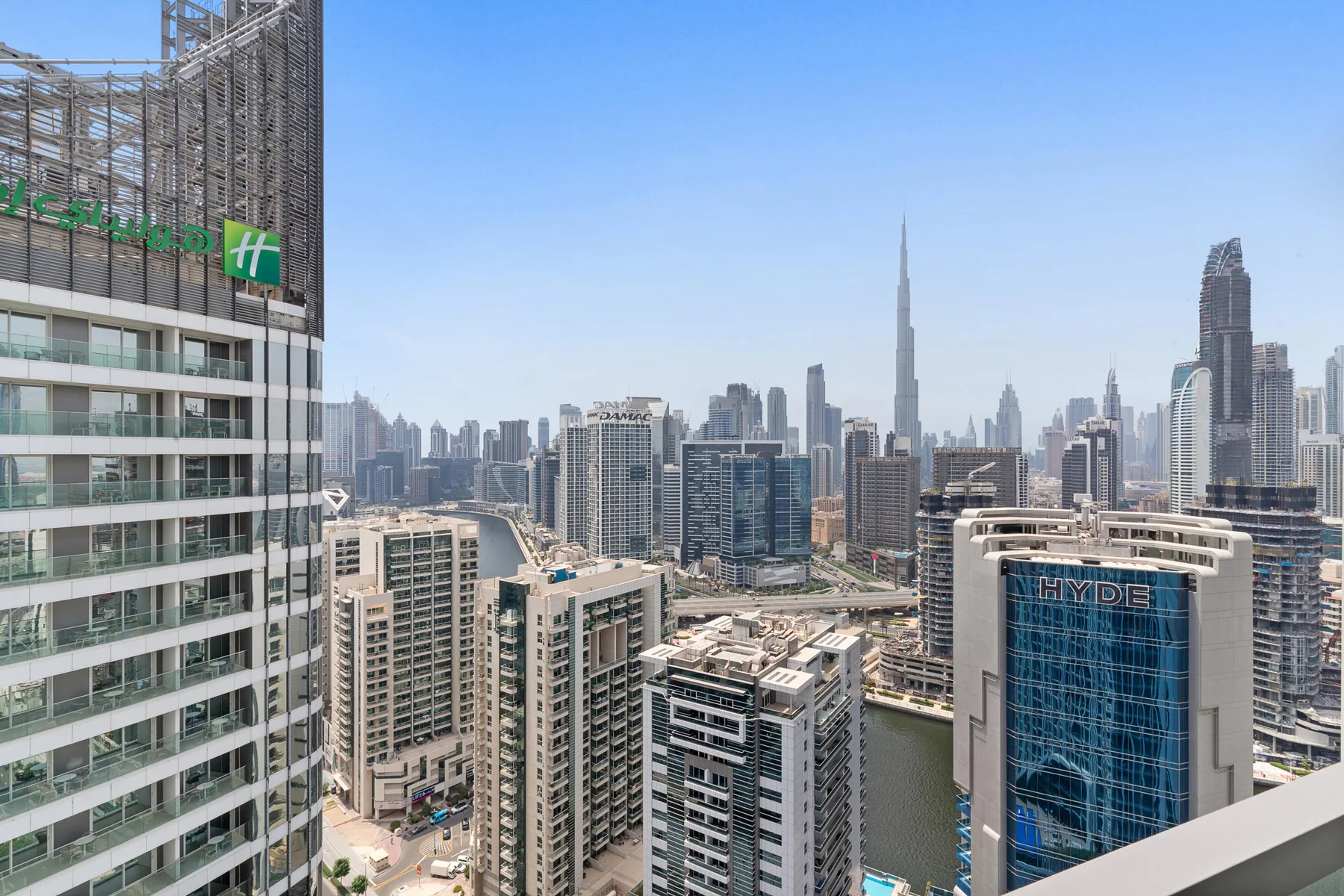 Un horizonte urbano con edificios altos y el Burj Khalifa visible a lo lejos.