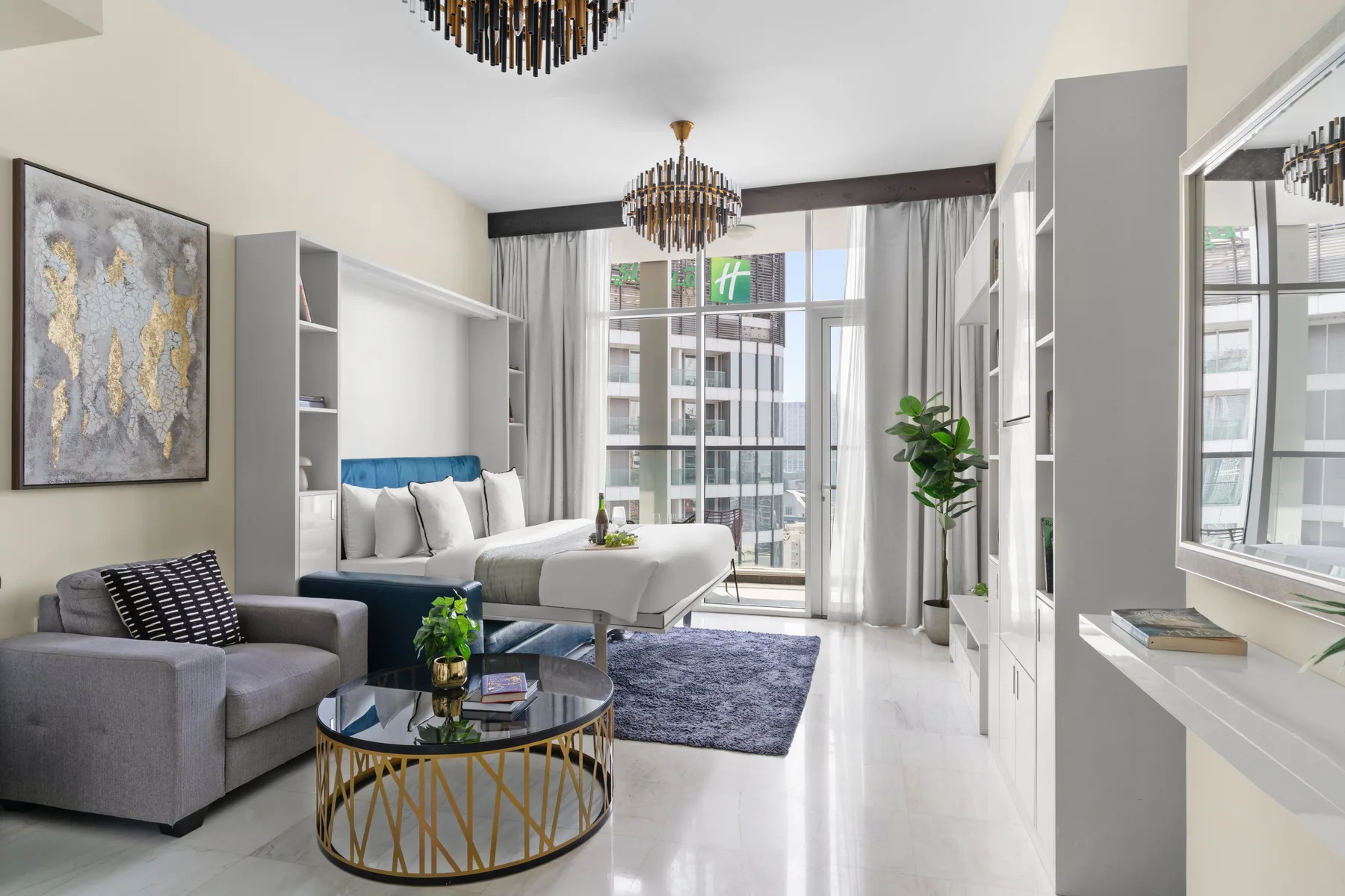 Una luminosa habitación tipo estudio con cama, asientos y grandes ventanas.