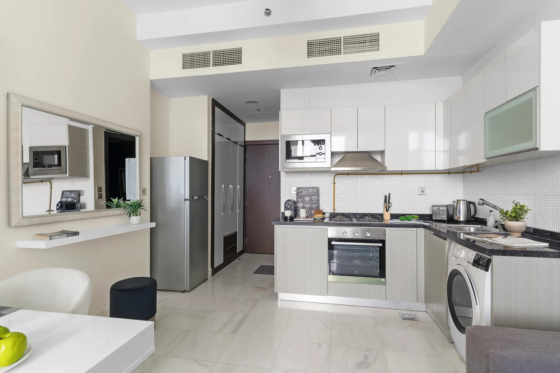 Una cocina moderna y luminosa con gabinetes blancos, horno y mesa de comedor.