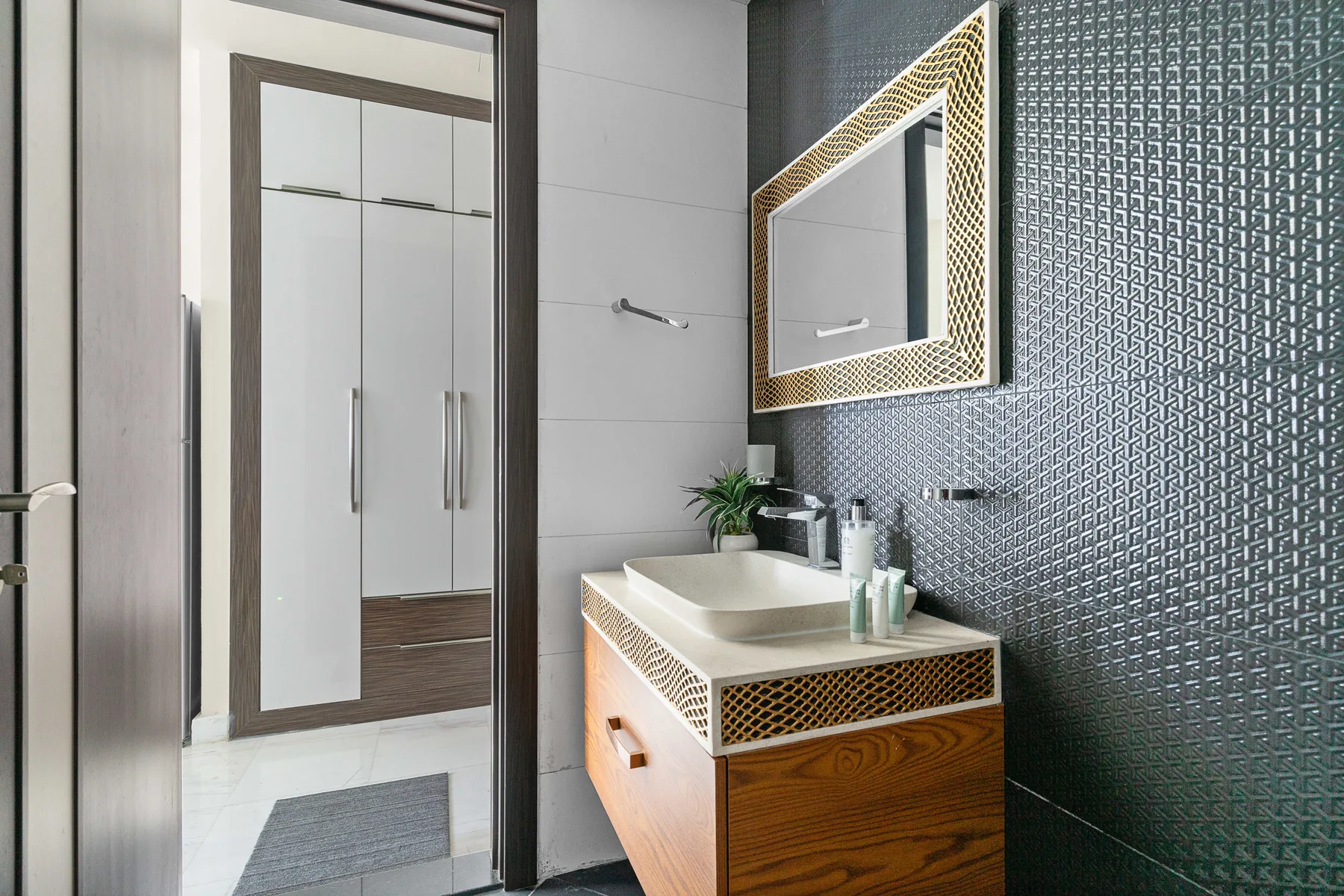 Un tocador de baño moderno con lavabo está junto a una pared oscura estampada.