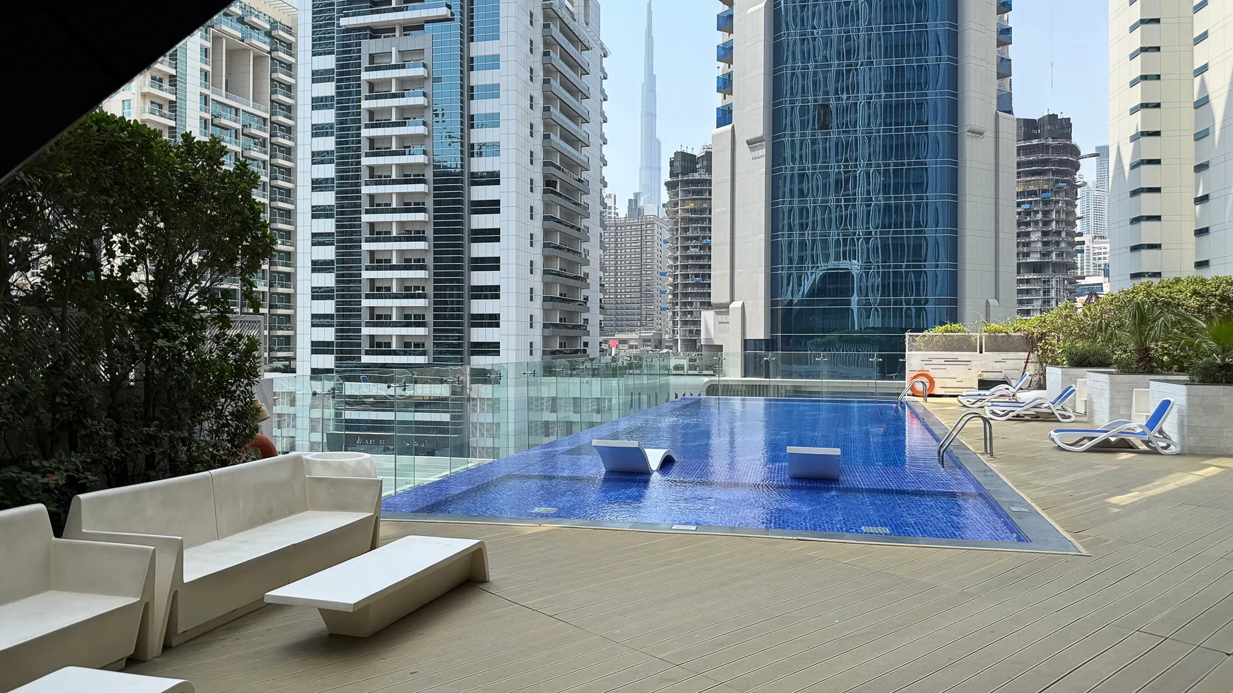 Una piscina en la azotea está rodeada de asientos y edificios altos de la ciudad.
