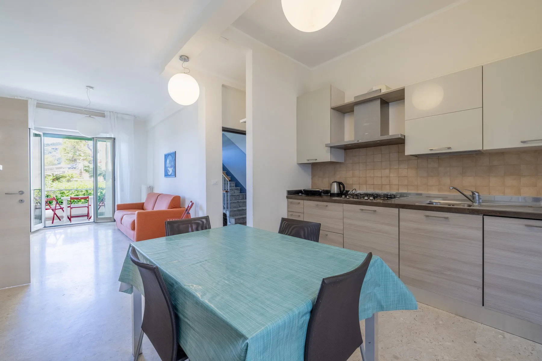 Un comedor con una mesa cubierta de turquesa junto a una cocina abierta y sala de estar.