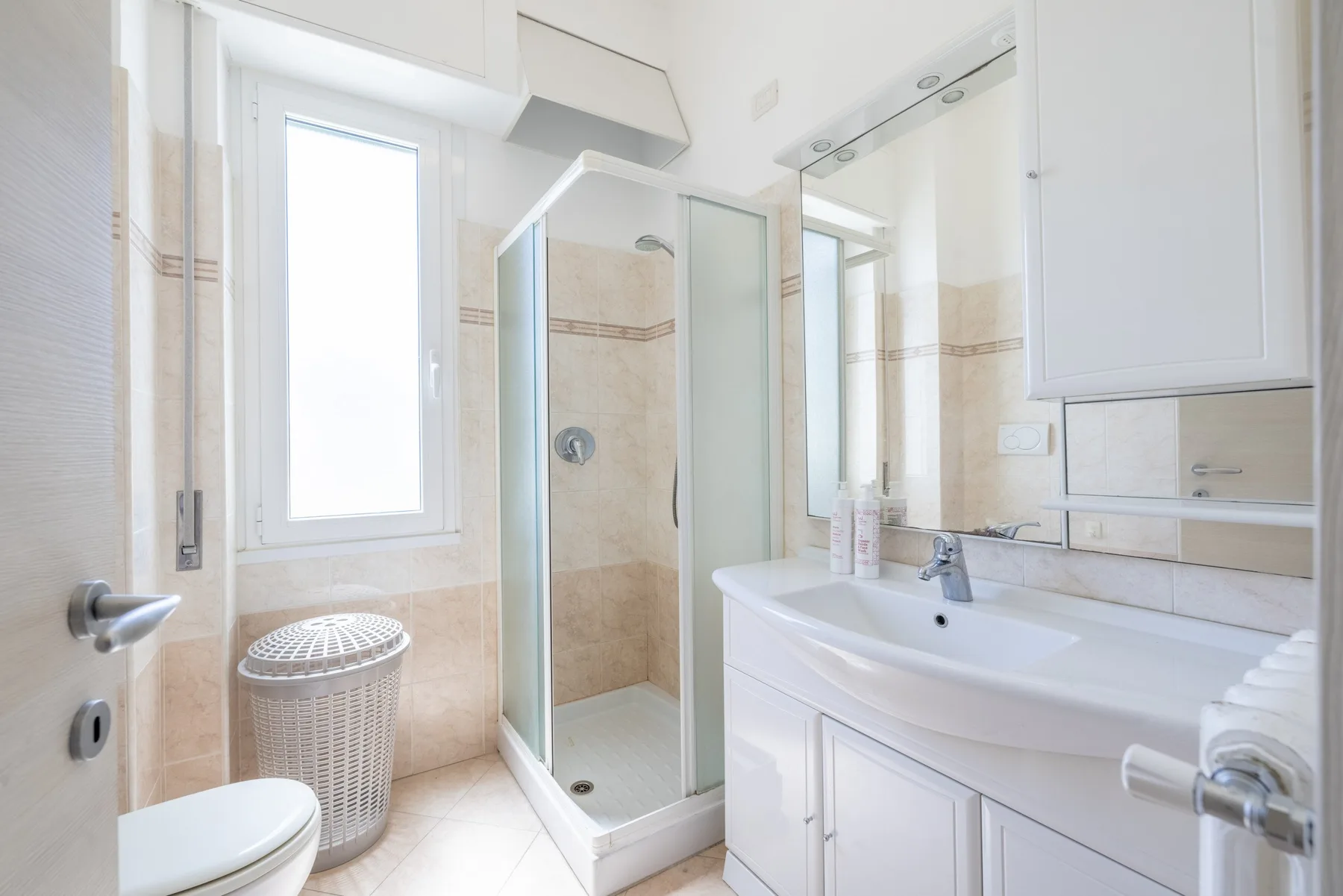 Un baño luminoso con ducha de vidrio, lavabo y ventana.