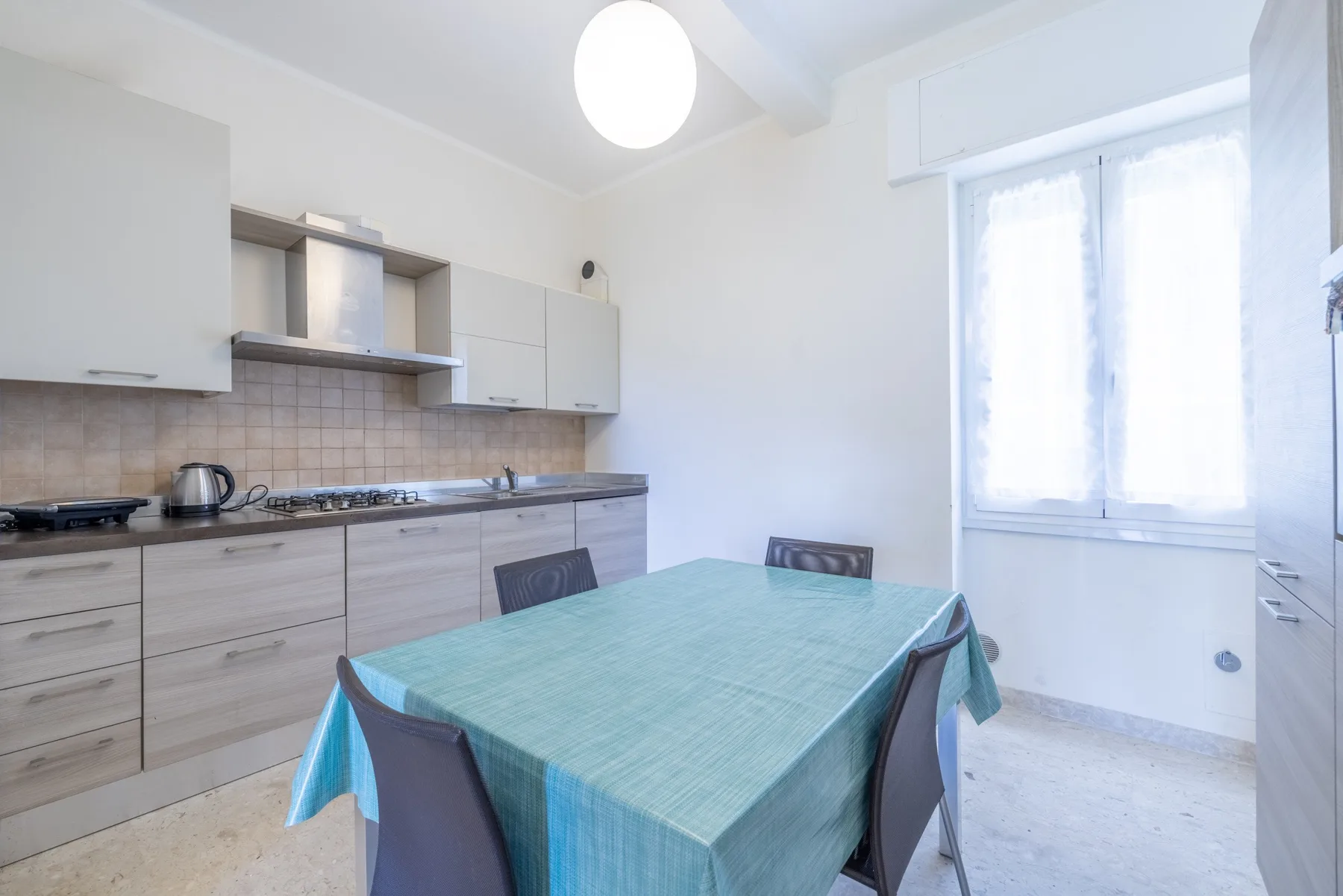 Una cocina luminosa con una mesa de comedor cubierta por un mantel turquesa.