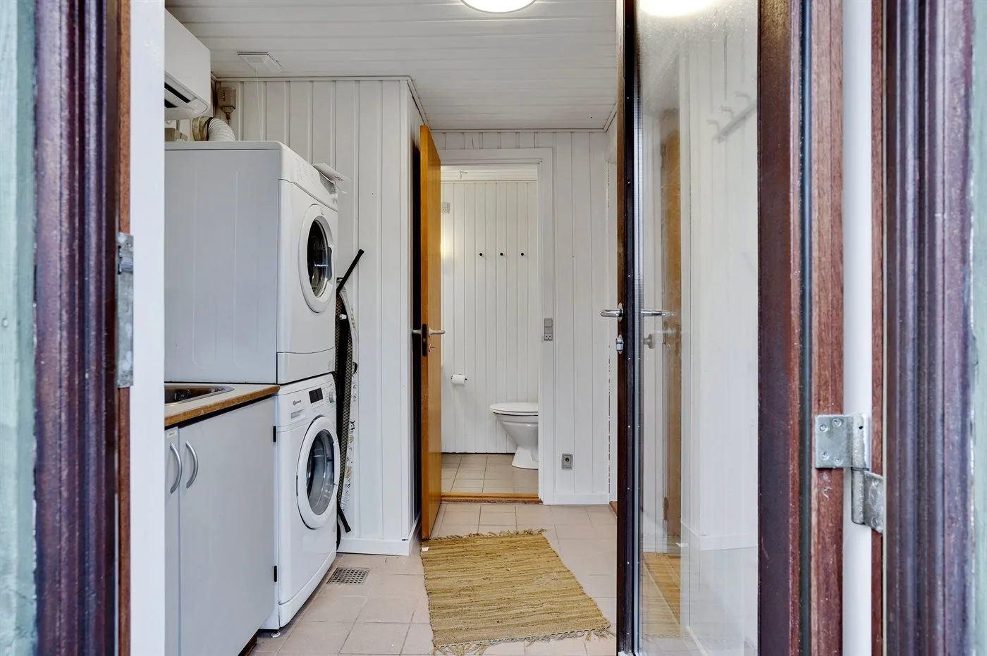 A laundry area with a washing machine and a doorway to a bathroom.