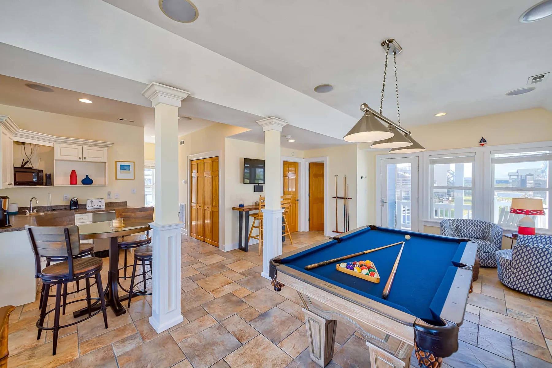 A game room with a blue pool table beside a seating area.