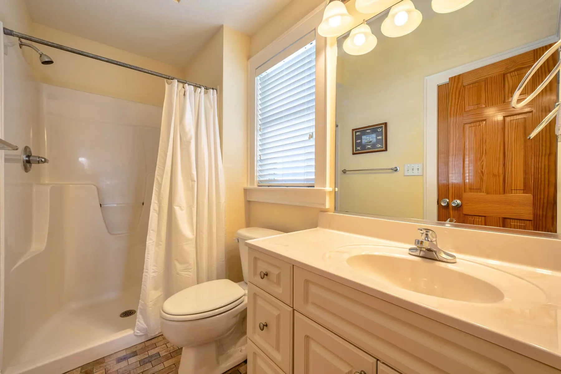 A bathroom with a bathtub and shower curtain beside a vanity and mirror.