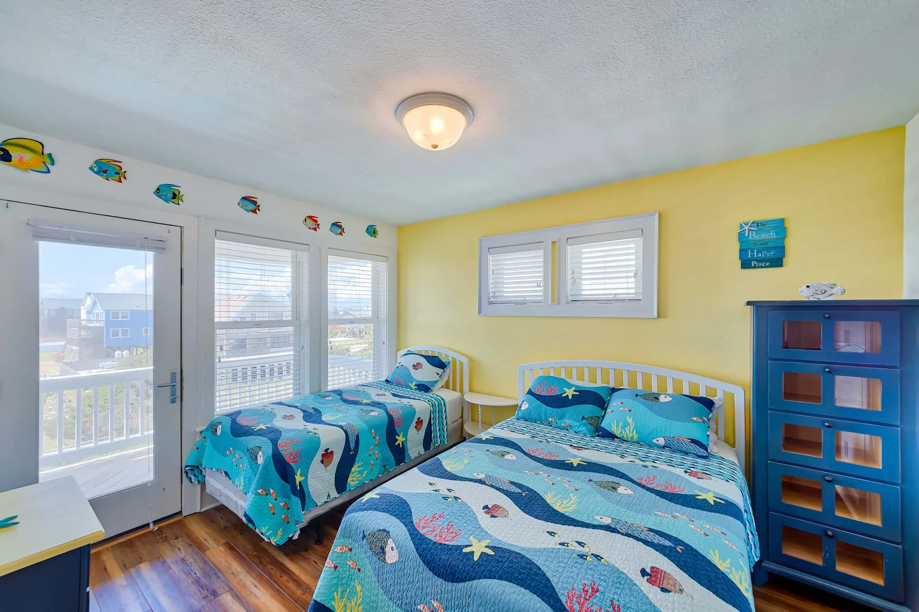 A bright bedroom with two beds dressed in blue patterned bedding.