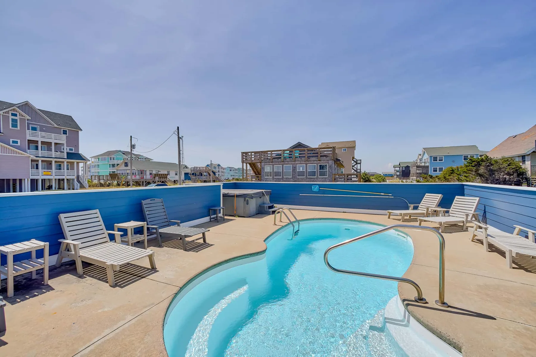 Outdoor pool area with lounge seating and blue privacy fencing.