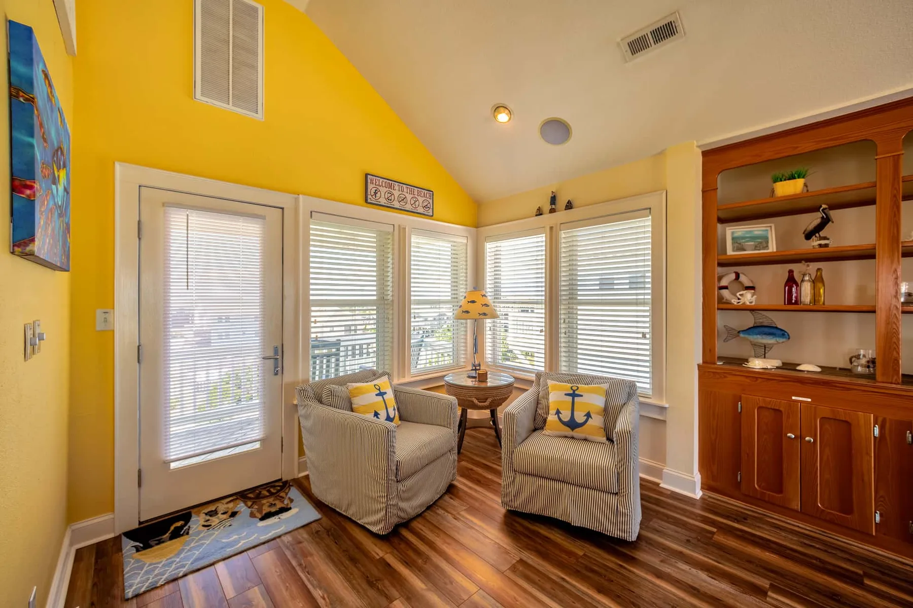 A bright sitting area with striped seating beside large windows and a built-in cabinet.