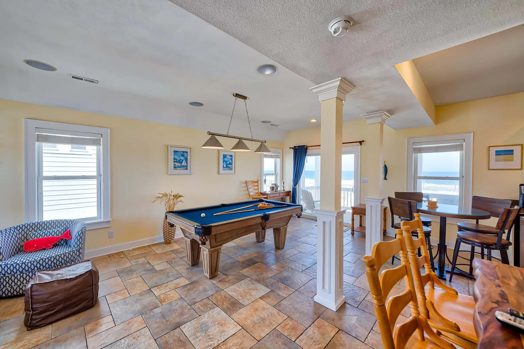 A bright game room features a pool table and dining area.