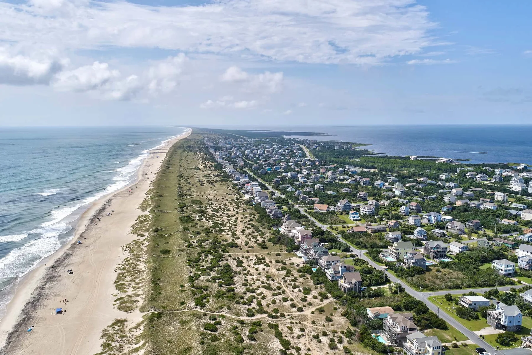 Aerial view of a coastal neighborhood beside a long sandy beach.