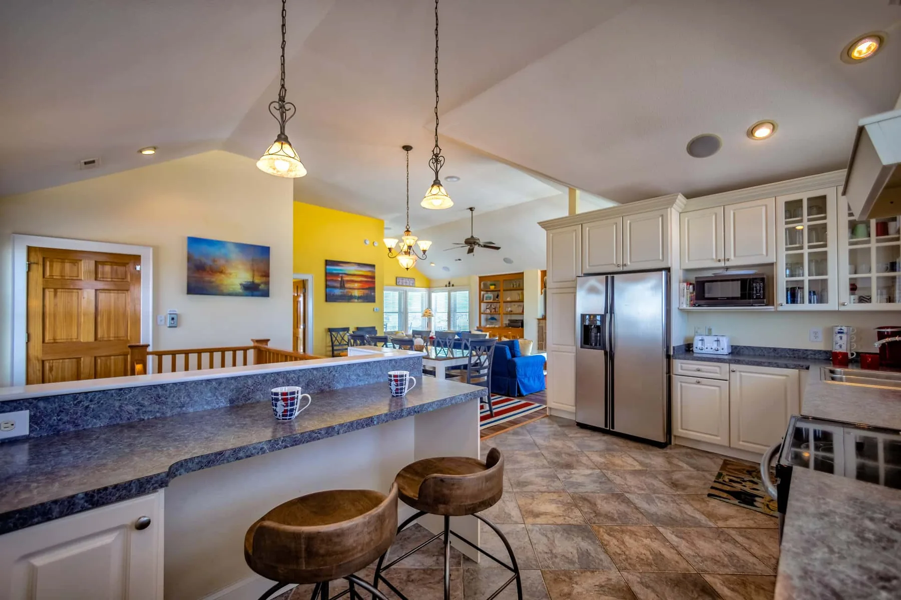 An open kitchen and dining area with a long counter and pendant lights.