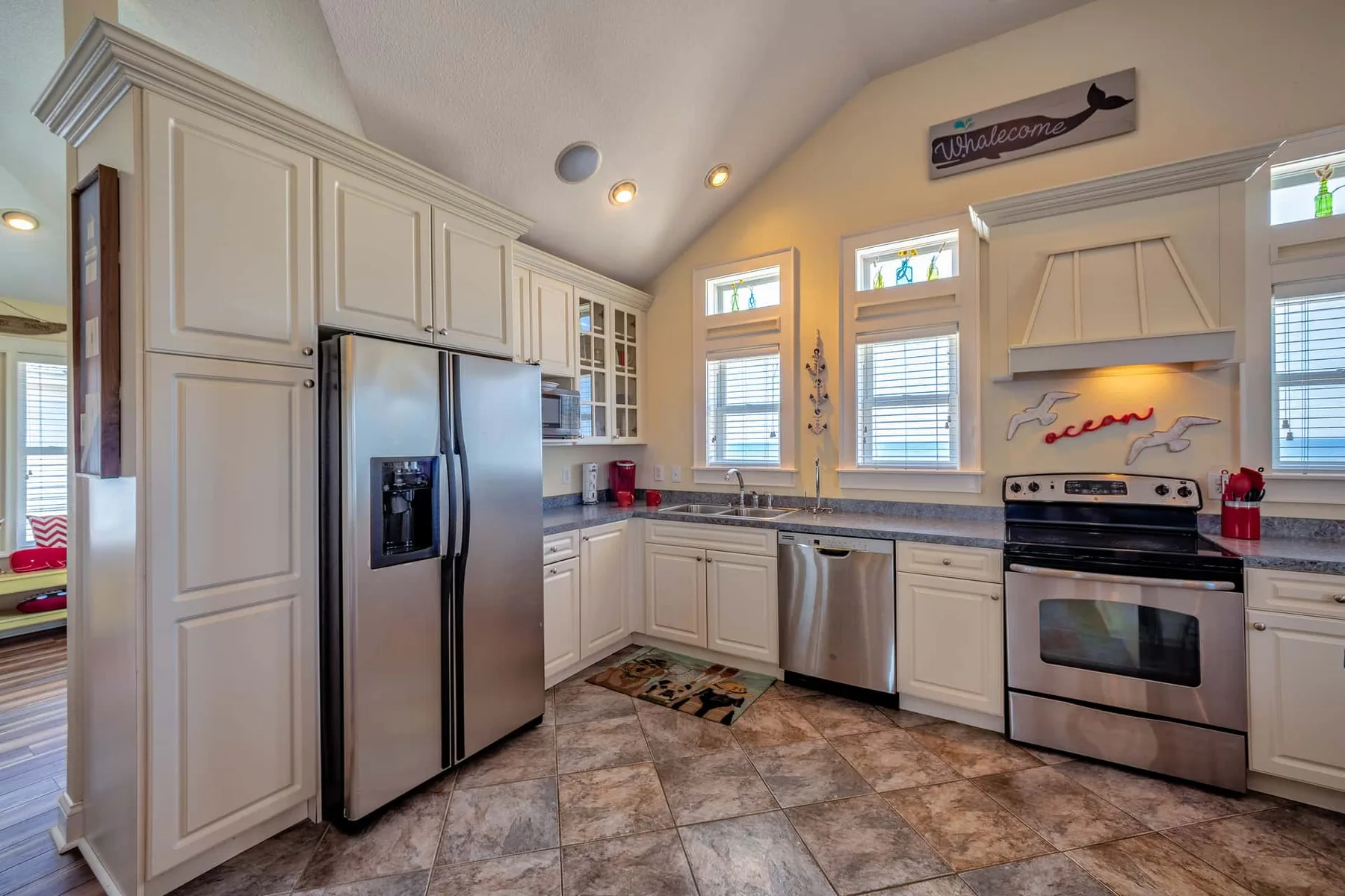 A bright kitchen with white cabinetry, stainless steel appliances, and windows above the counters.