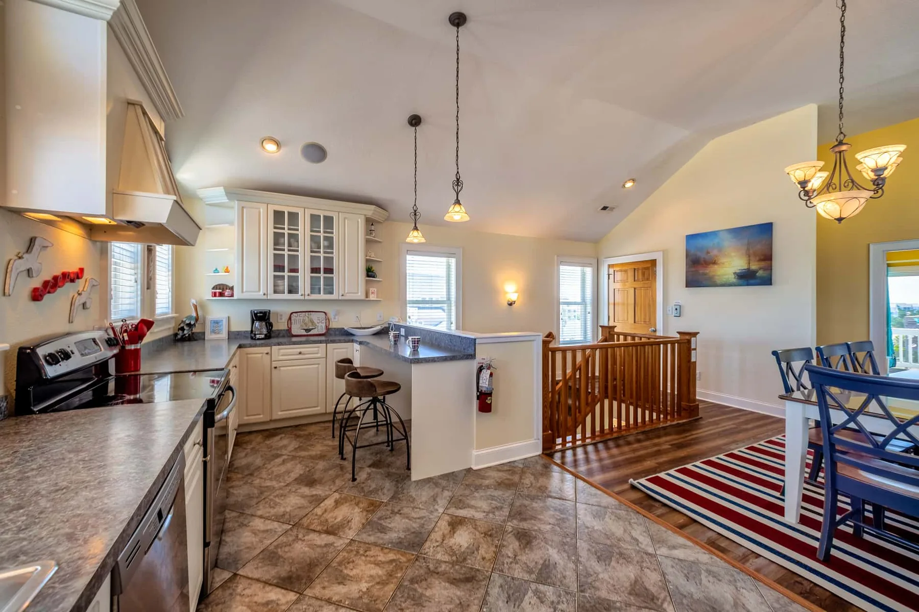 An open kitchen and dining area with a central island and wooden railing.