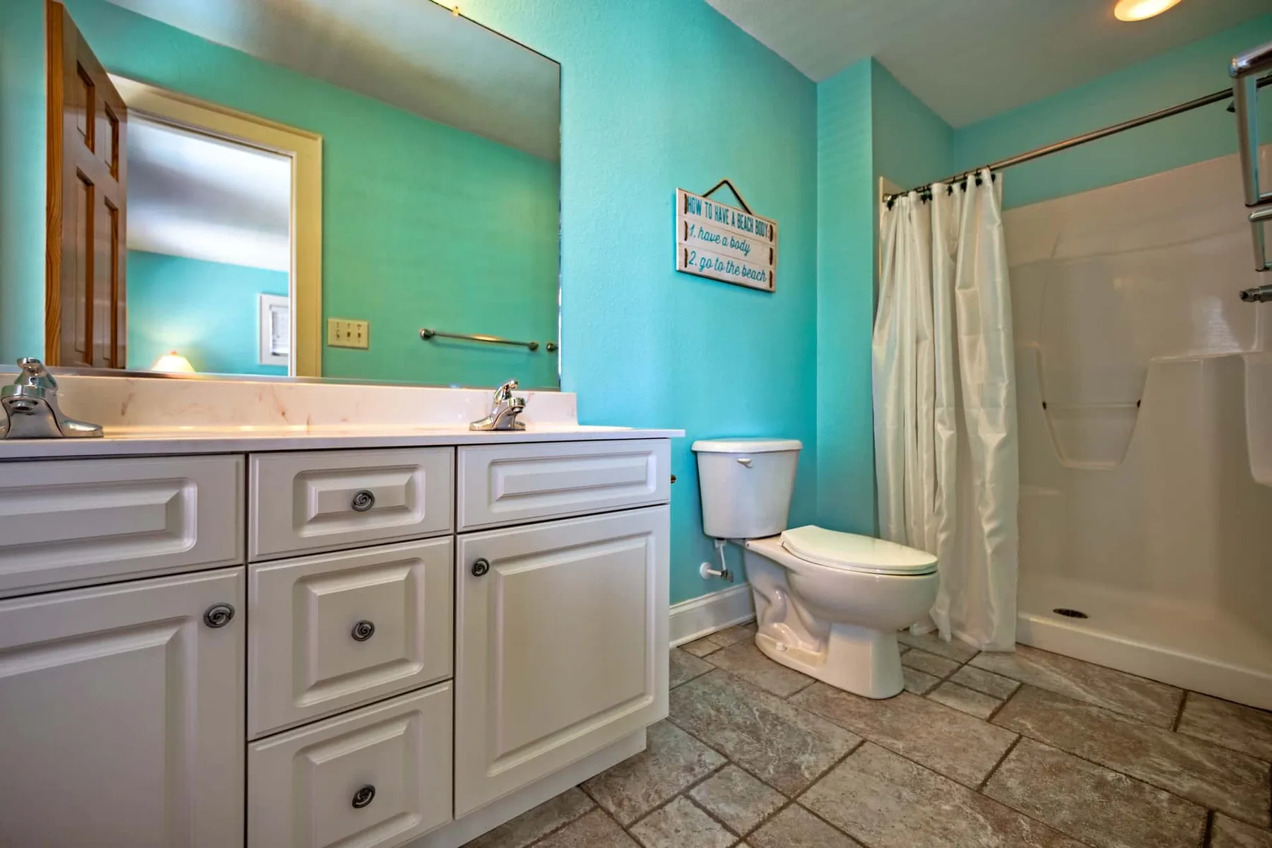 A bathroom with a white vanity, toilet, and shower.