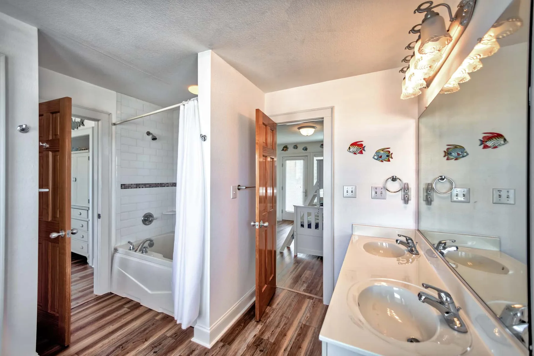 A bright bathroom with a double sink vanity, bathtub, and shower.