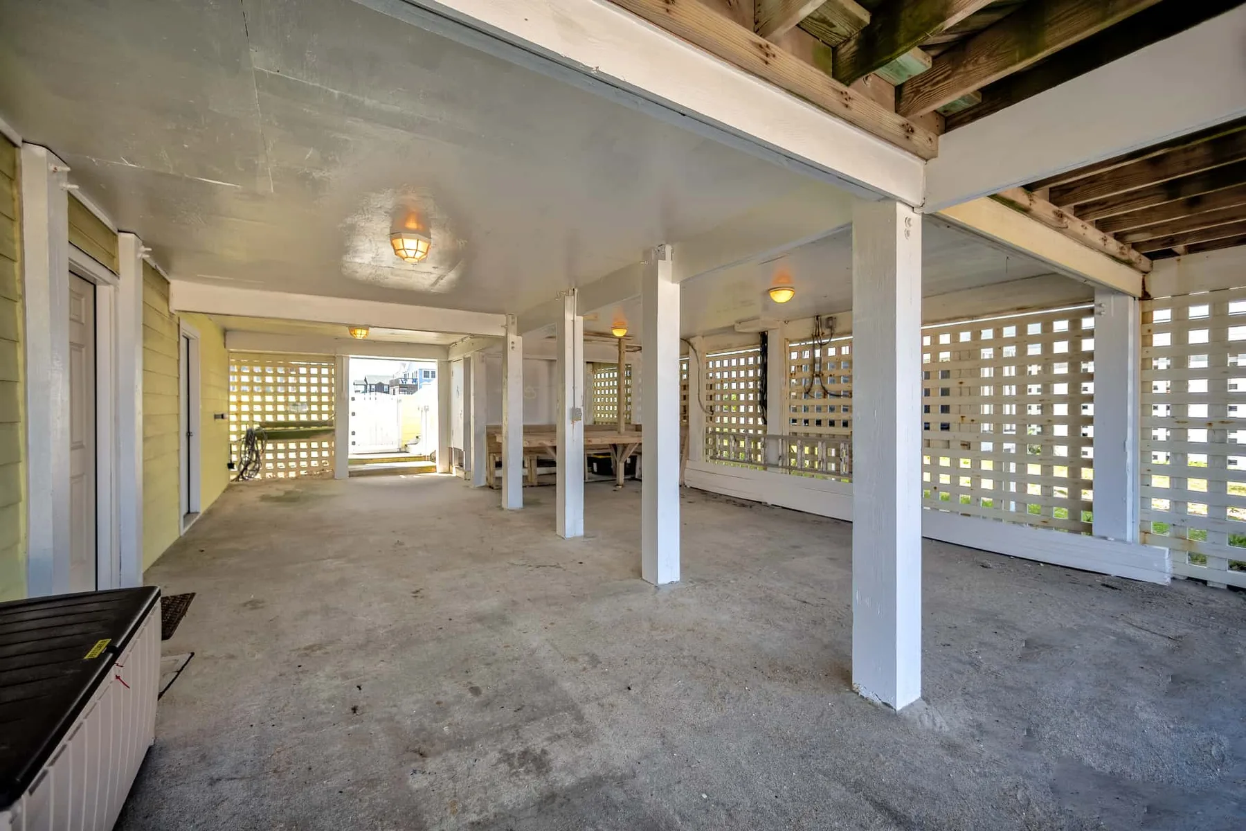 A covered outdoor patio with support posts and lattice privacy screens.