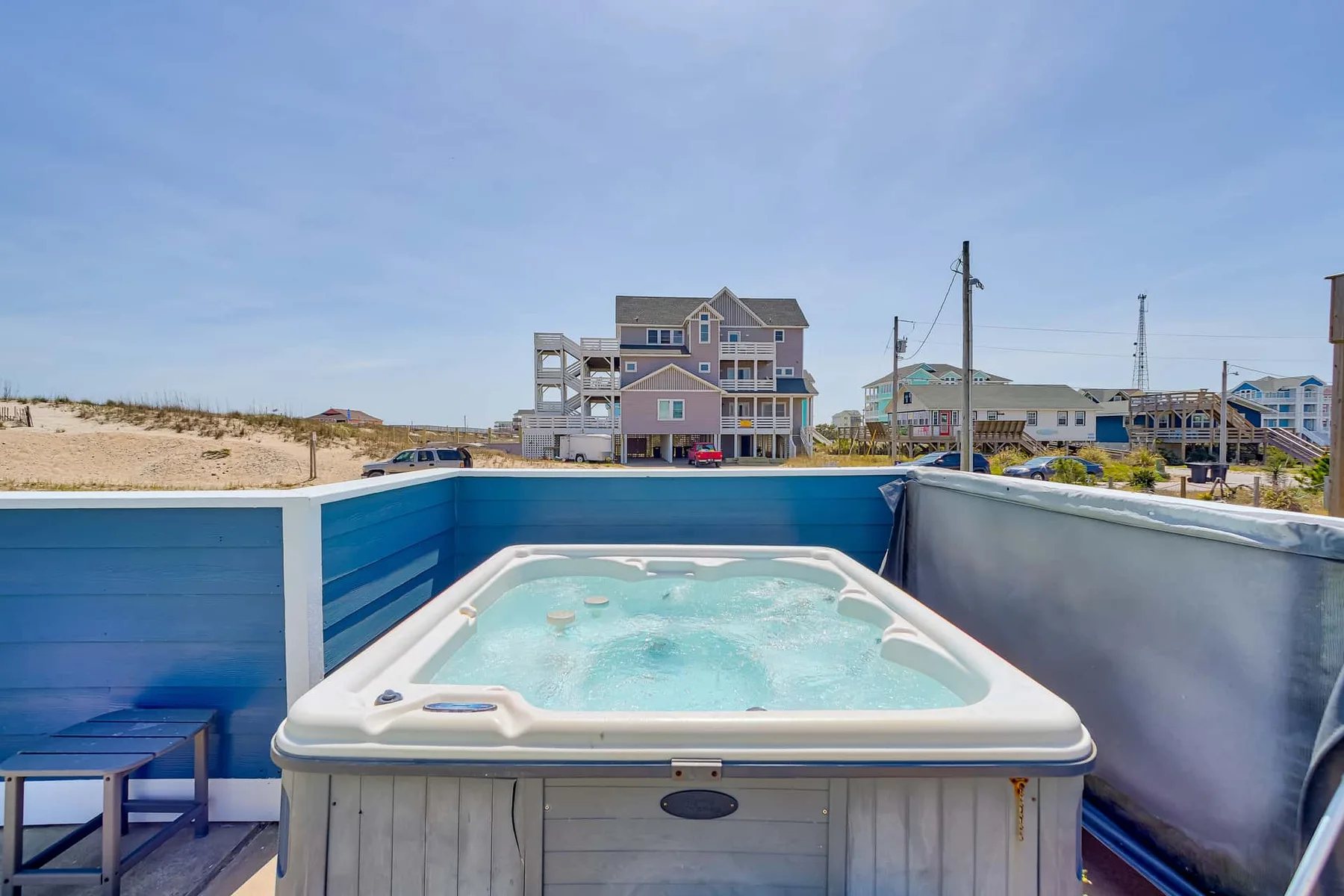 A hot tub sits on an outdoor deck beside blue privacy panels.