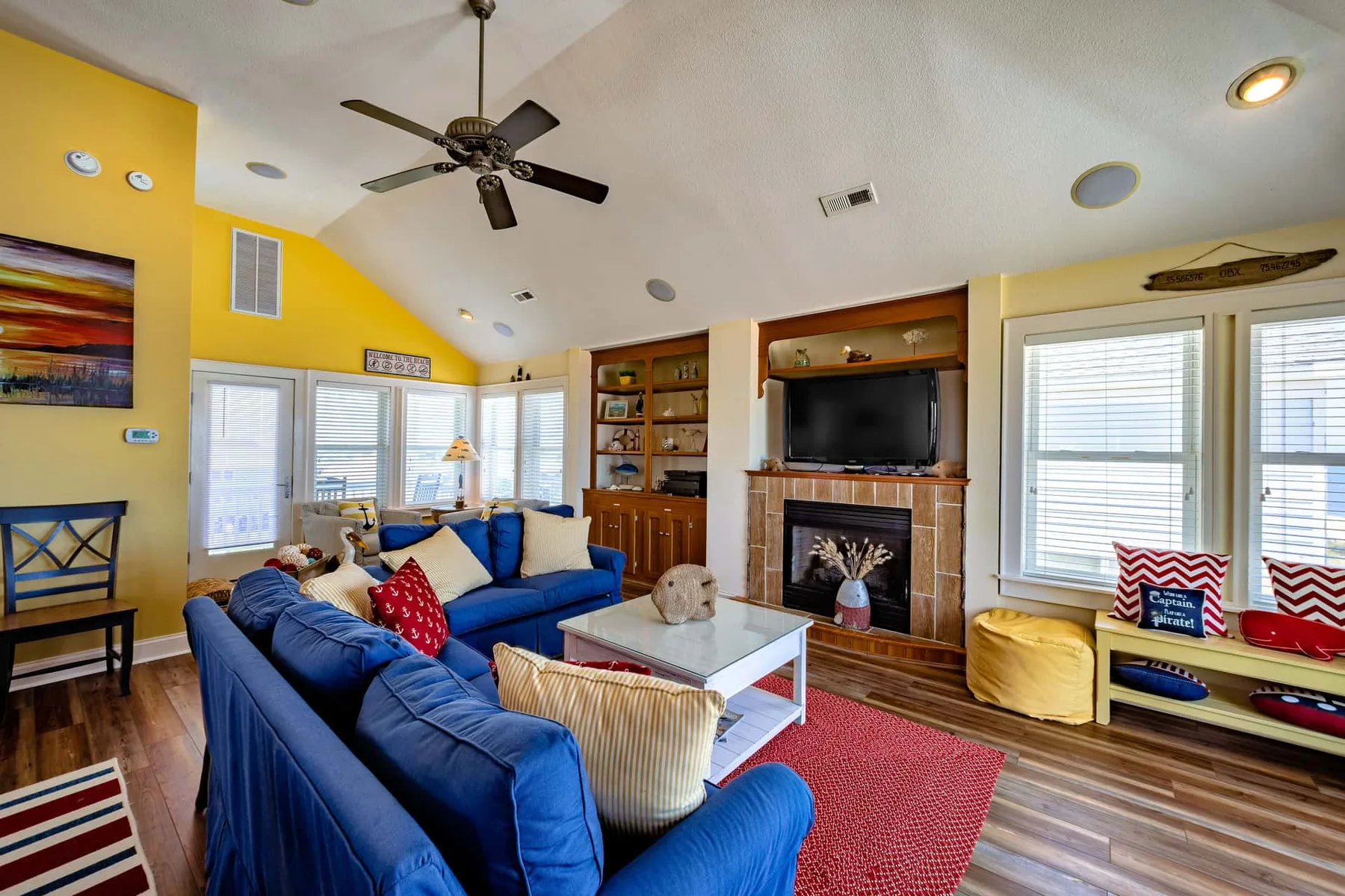 A bright living room with blue seating, a fireplace, and large windows.