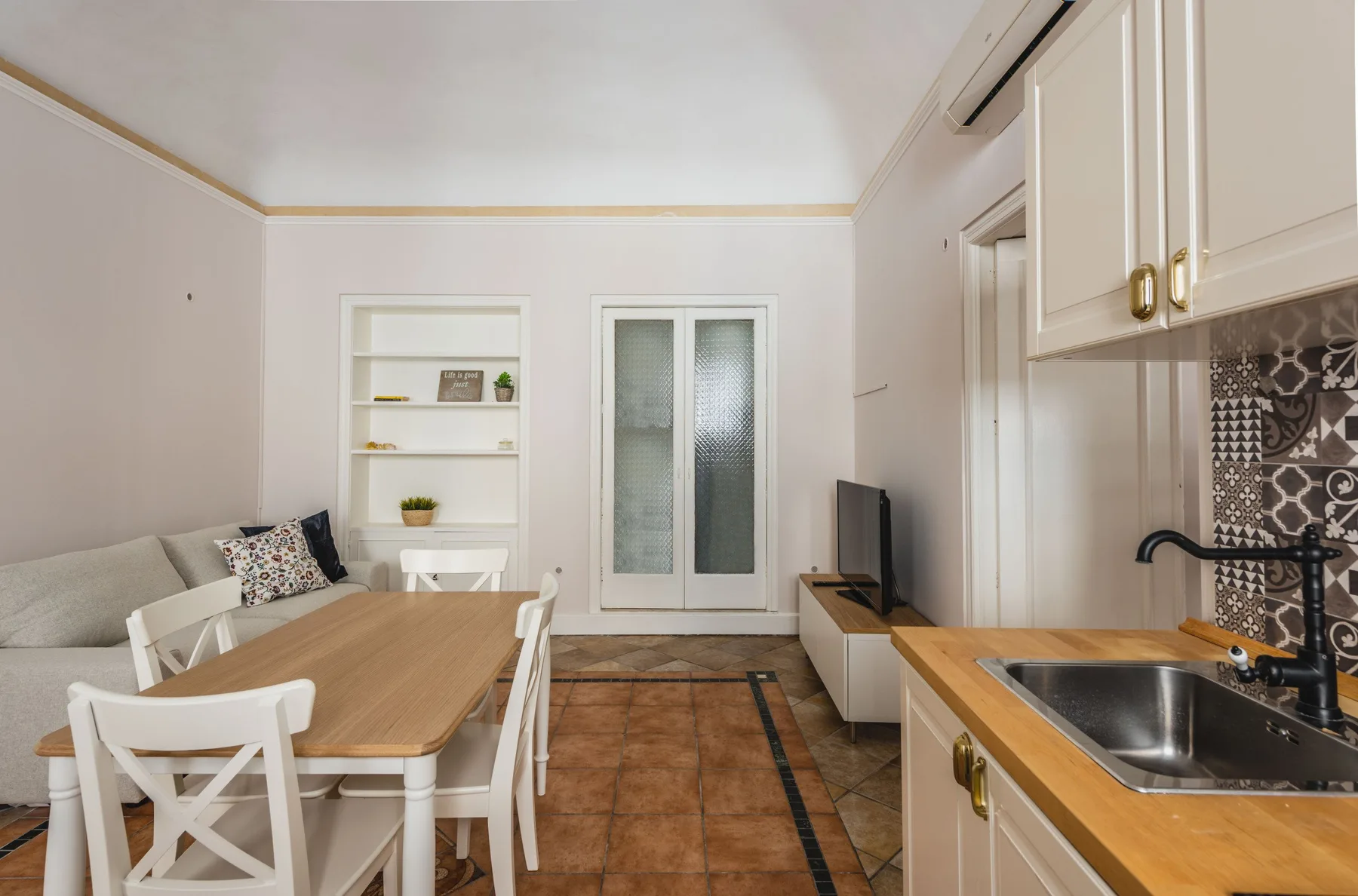 Una zona de estar y comedor junto a una cocina, con mesa y asientos.