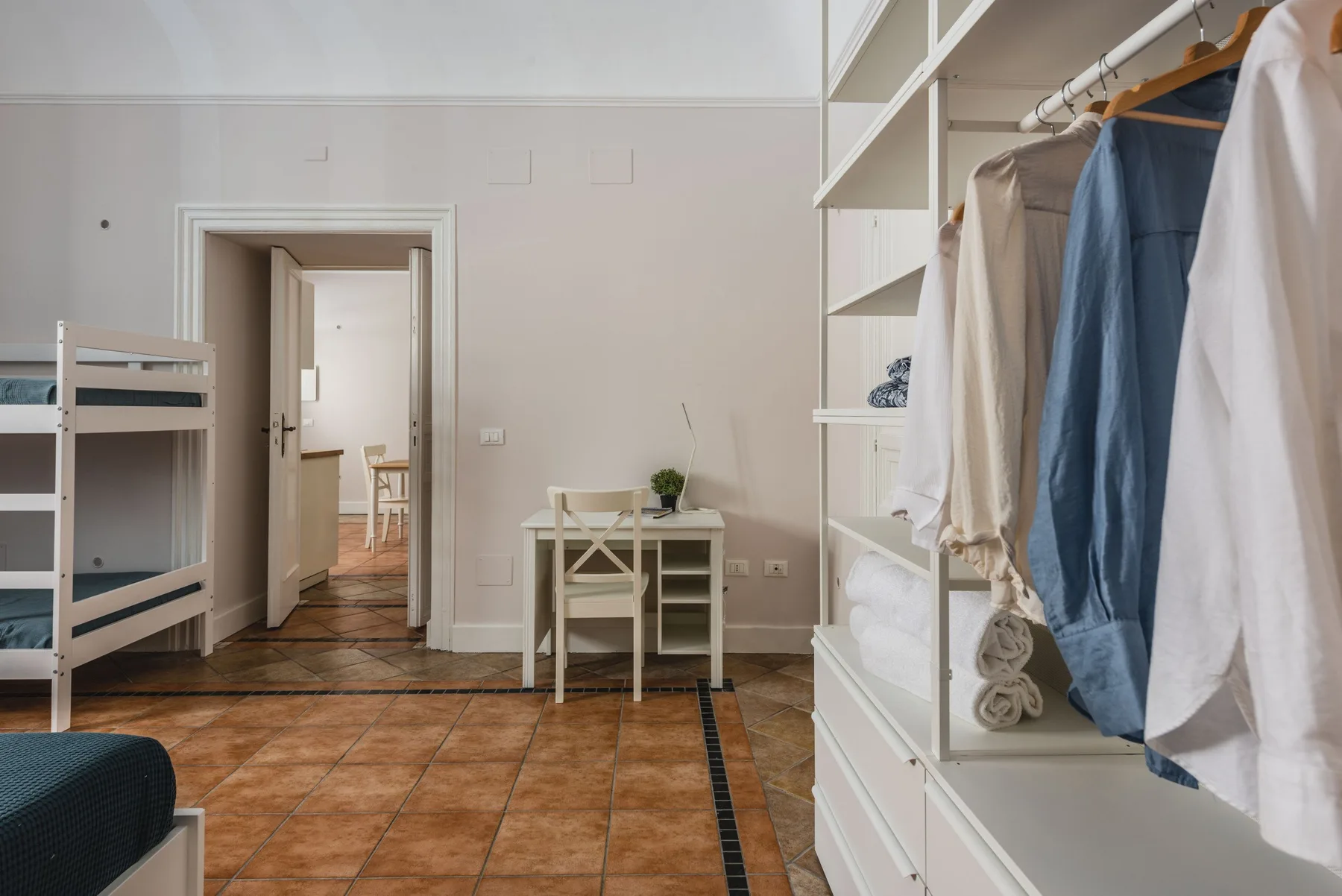 Un dormitorio con una litera y espacio de almacenamiento abierto para ropa.