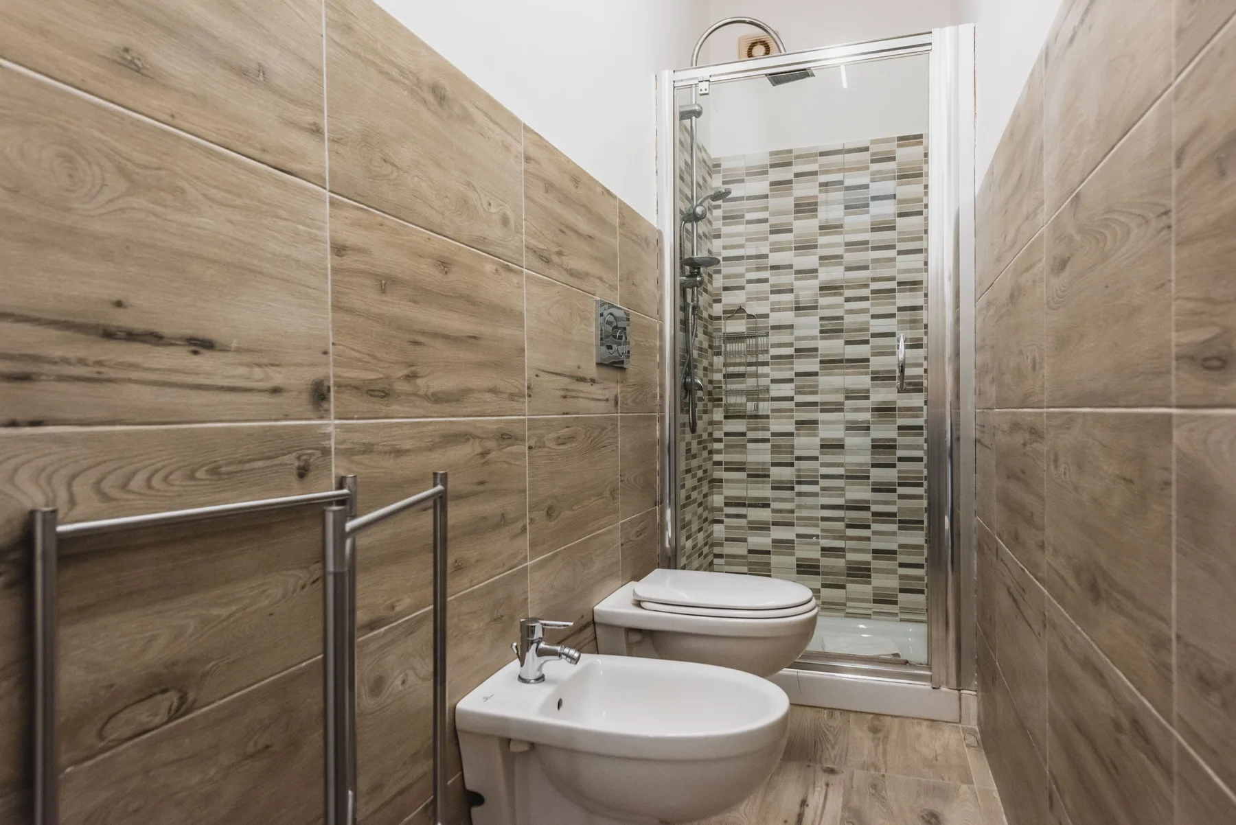 Un baño revestido de azulejos con lavabo, inodoro y zona de ducha.