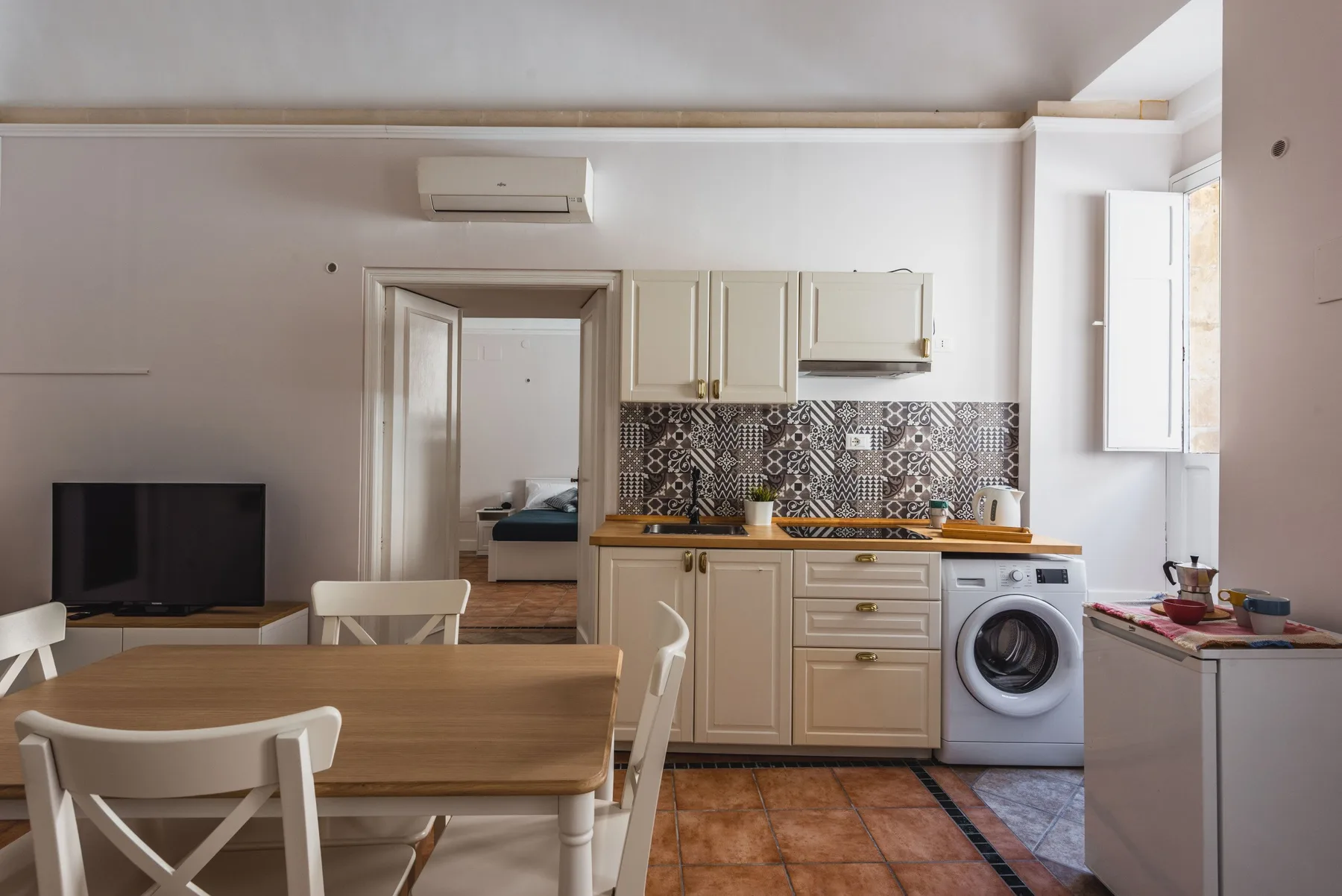 Cocina y comedor con una mesa, un televisor y un salpicadero estampado.