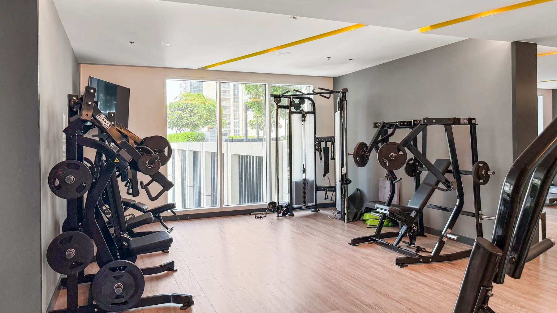 Un gimnasio interior luminoso con máquinas de pesas y grandes ventanas.