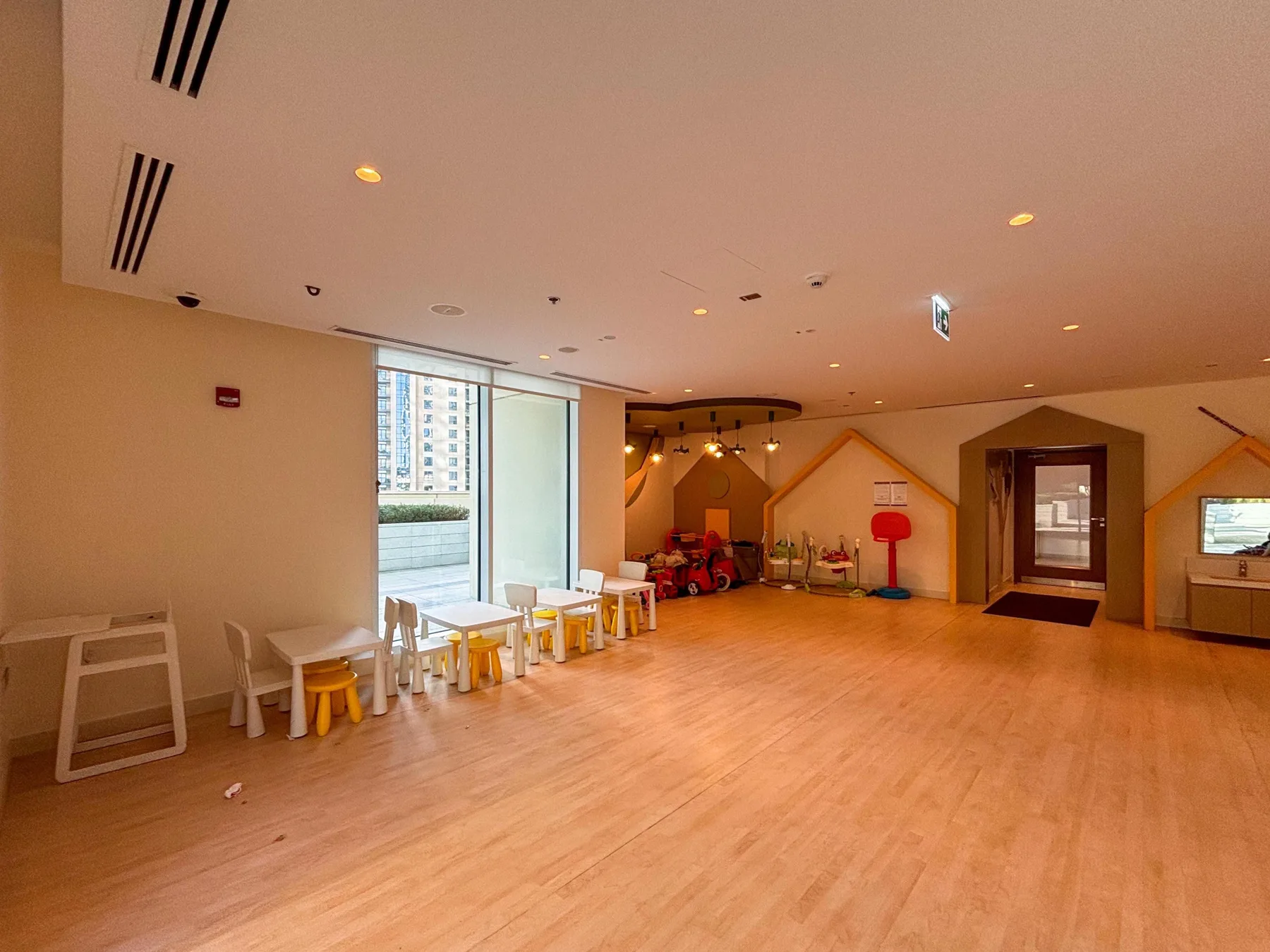 Una amplia sala de juegos interior con suelo de madera y asientos infantiles.