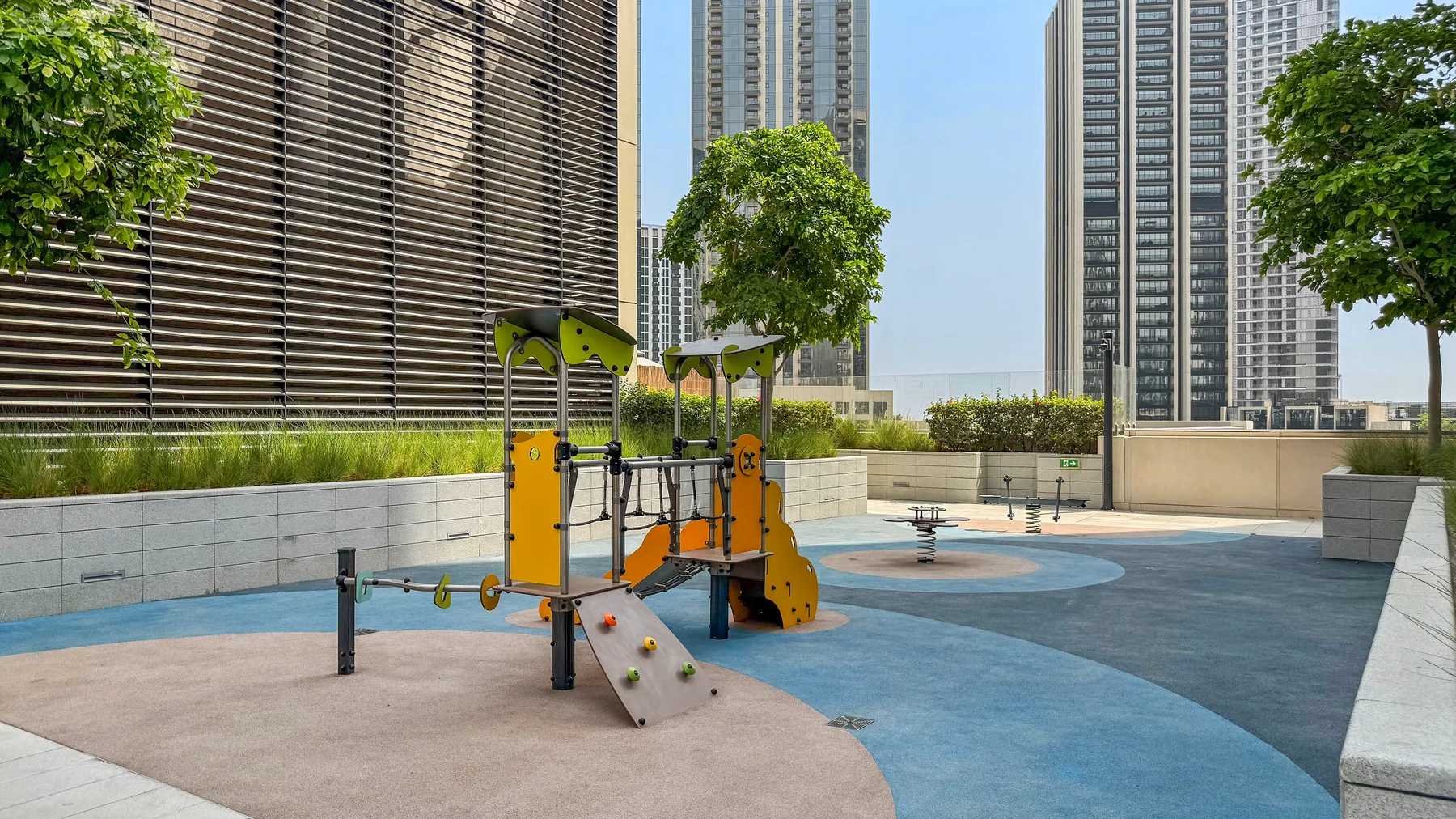 Un parque infantil al aire libre con juegos coloridos y suelo de caucho.