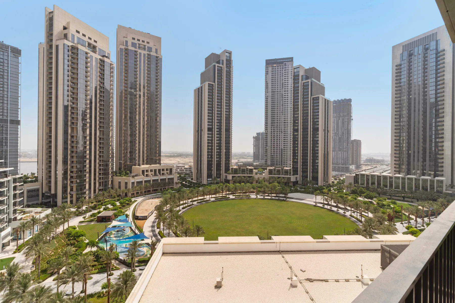 Un complejo residencial ajardinado rodea un césped central entre edificios altos.