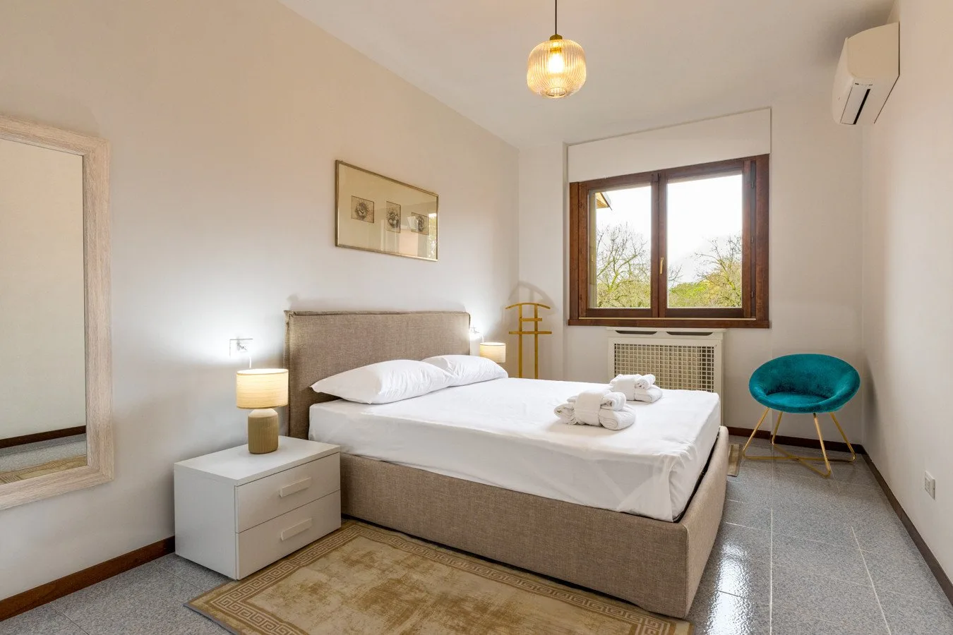 Un dormitorio con una cama bien arreglada bajo una ventana.