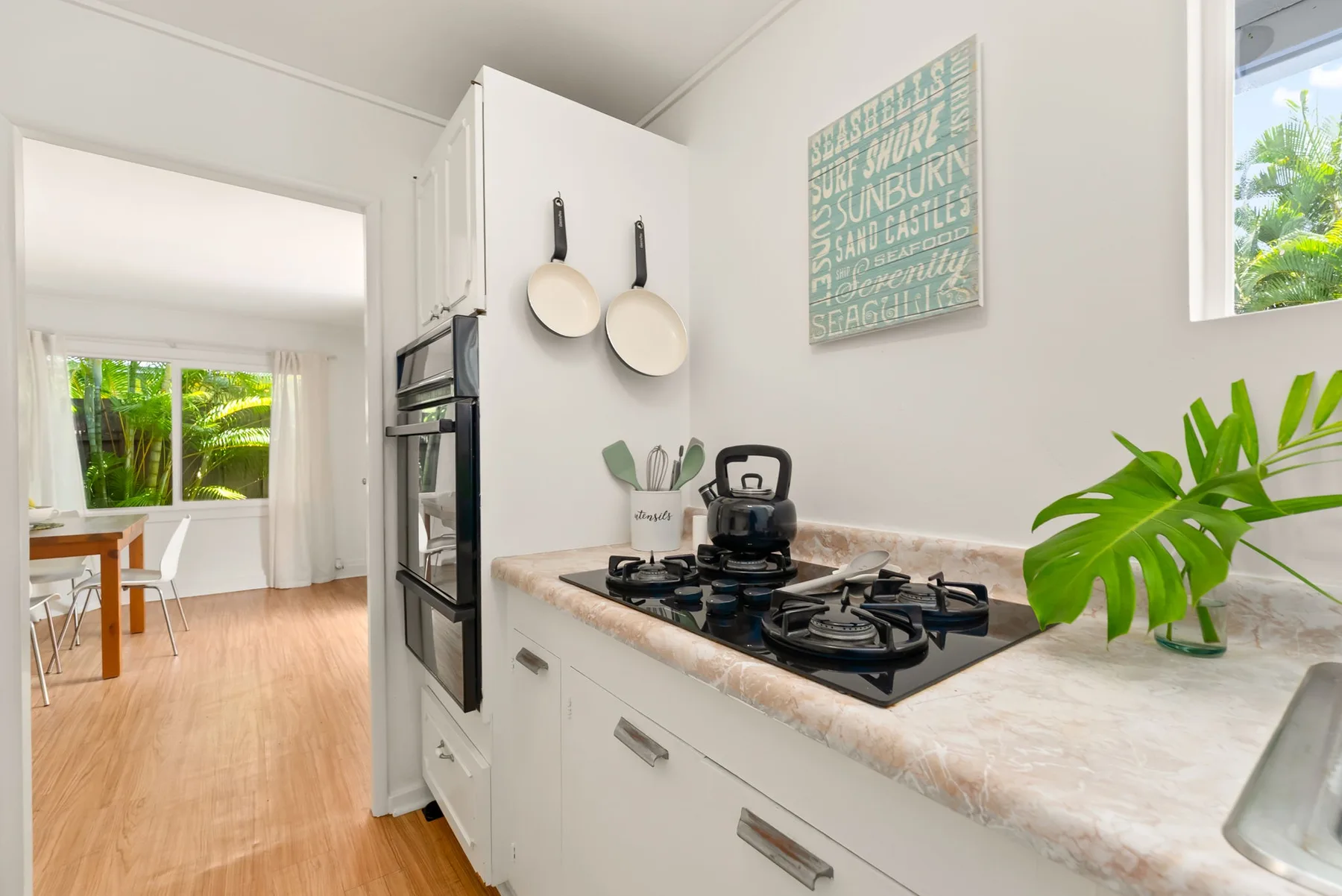 Una cocina luminosa con una placa de cocción y un comedor contiguo.