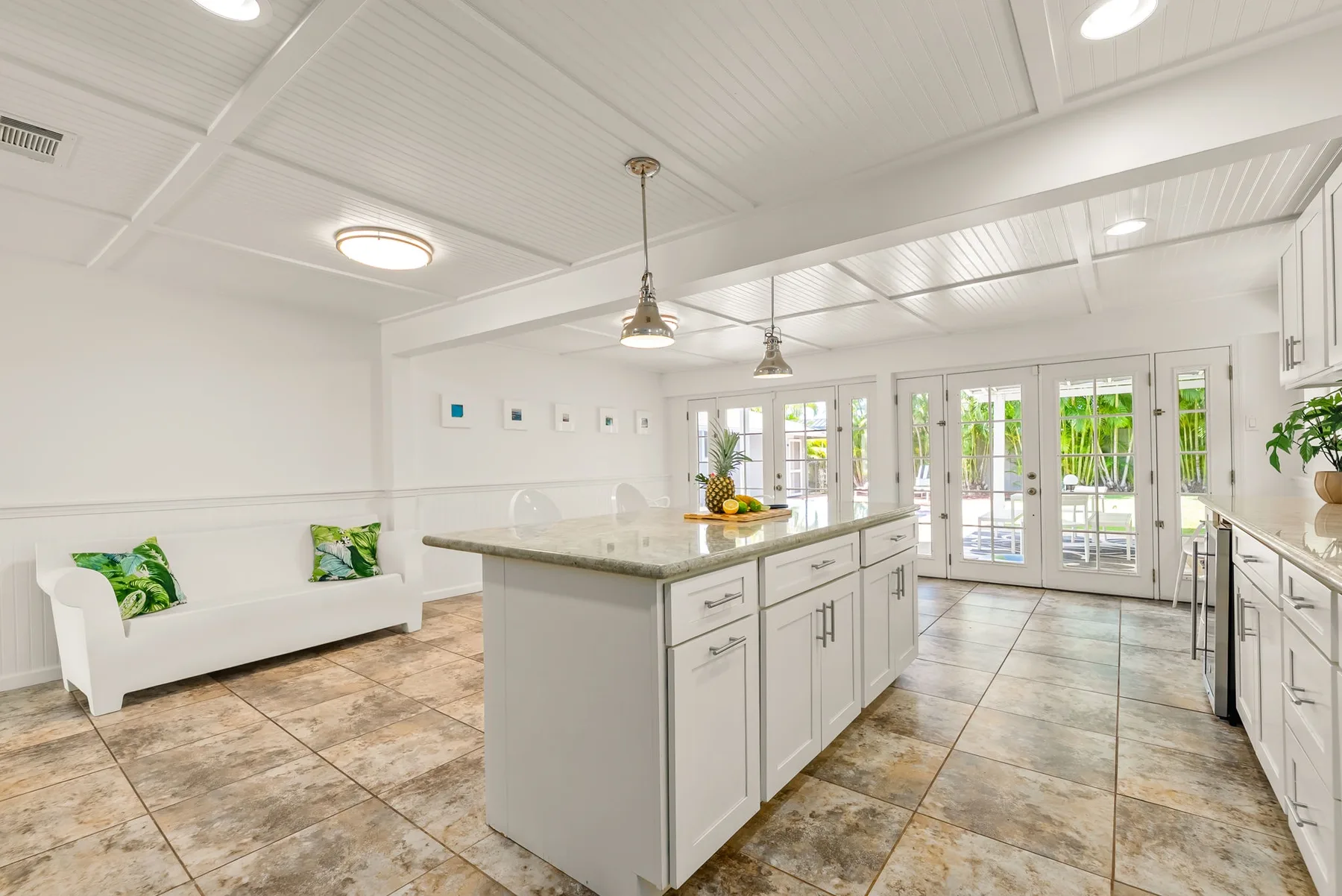 Una cocina luminosa con una isla central larga y puertas de vidrio.