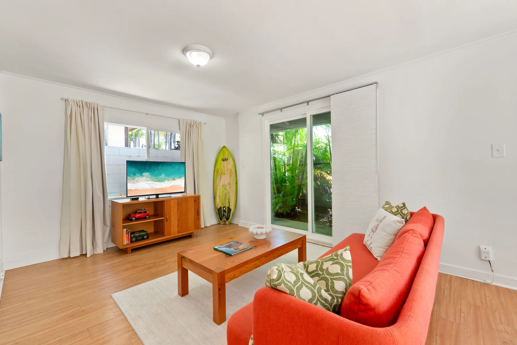 Una sala luminosa con sofá coral, mesa de centro de madera y puertas corredizas de vidrio.