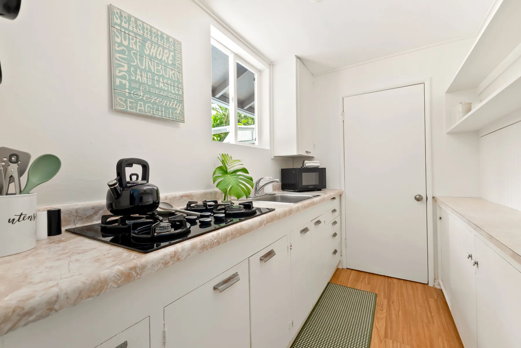 Una cocina luminosa con gabinetes blancos, una encimera y una estufa de gas.