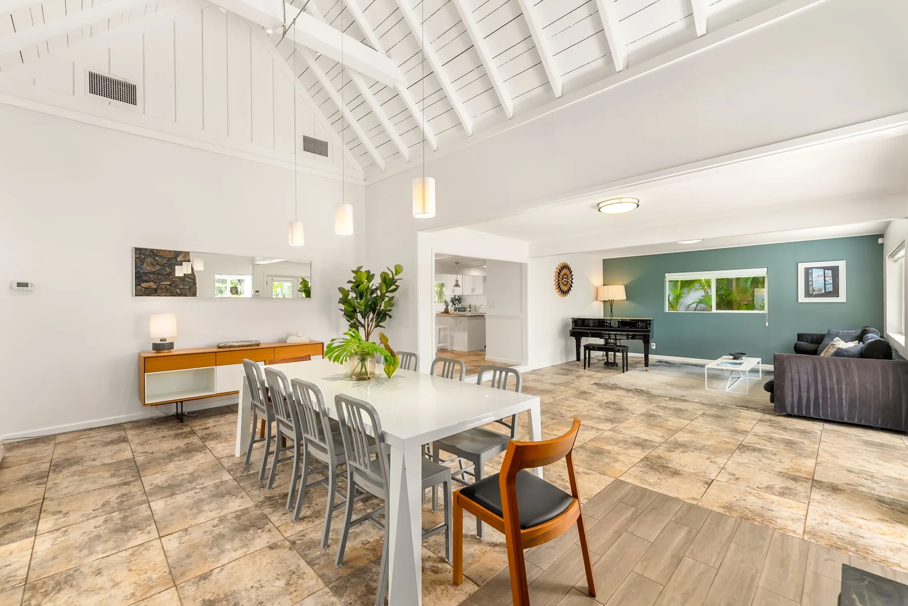 Un luminoso espacio diáfano de comedor y sala de estar con una mesa larga y asientos.