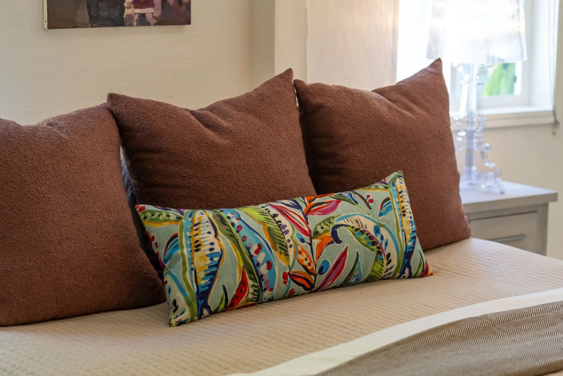 Un espacio para sentarse con cojines marrones y una almohada colorida estampada.
