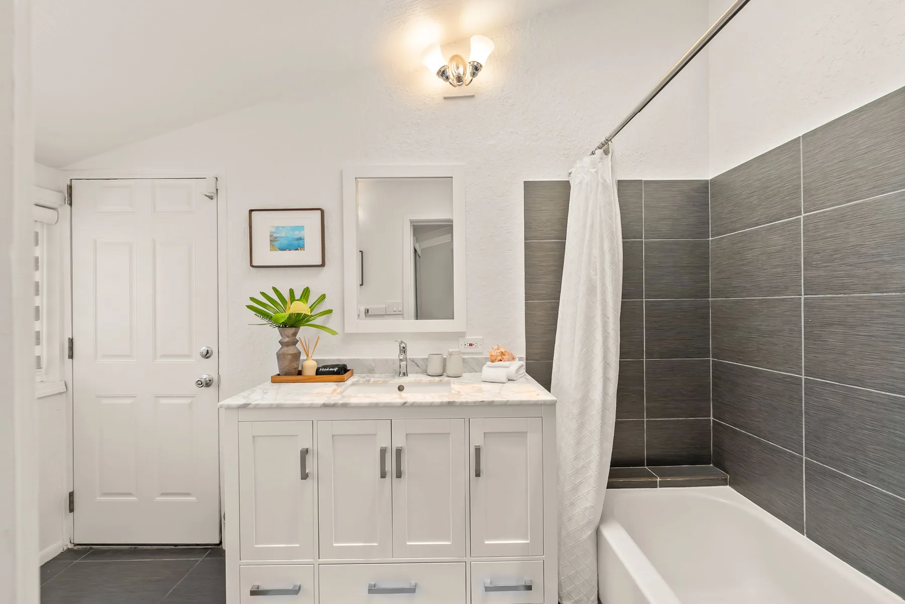 Un baño luminoso con un lavabo y tocador junto a una bañera con ducha.