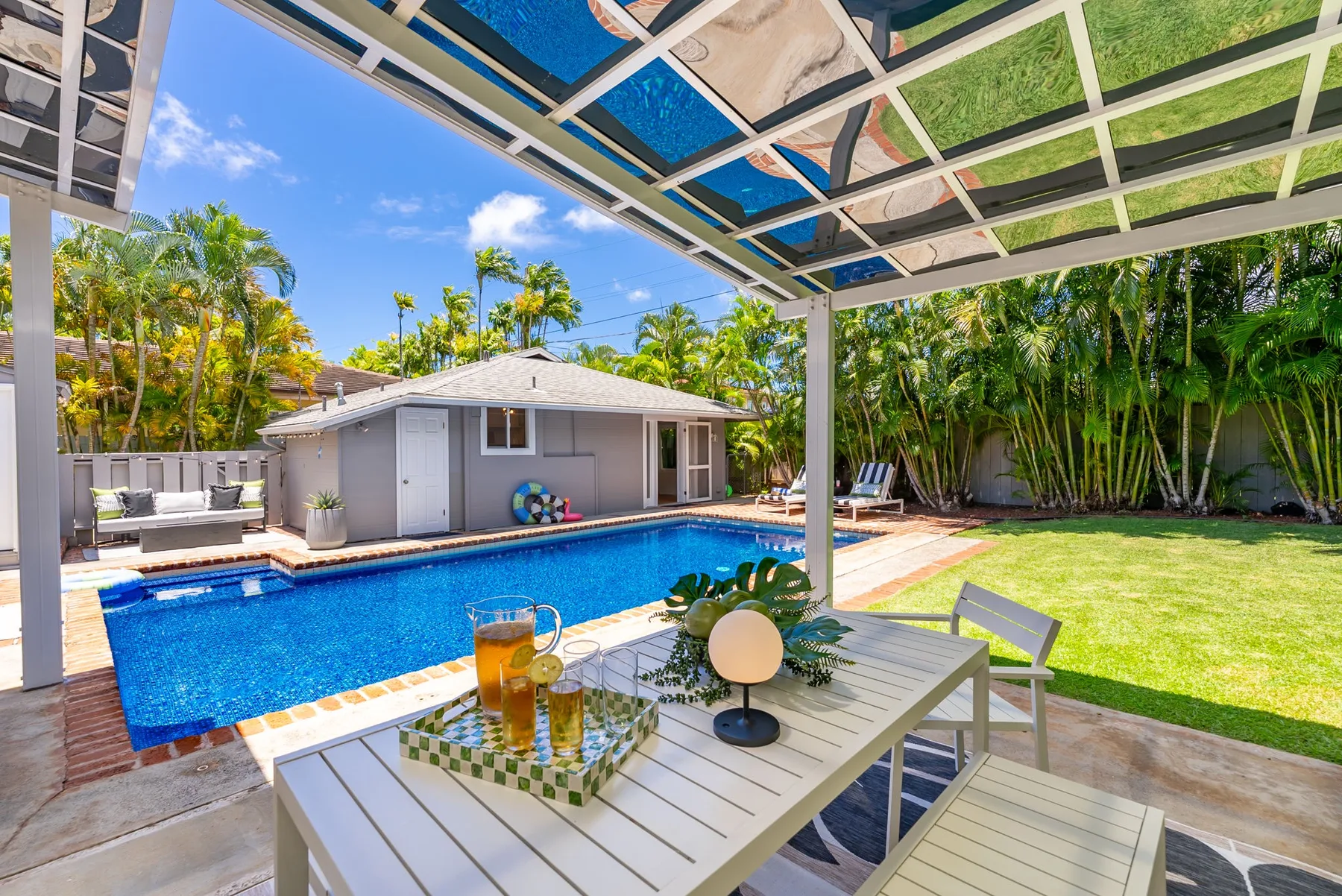 Una piscina y una zona de comedor en el patio están bajo una terraza cubierta.