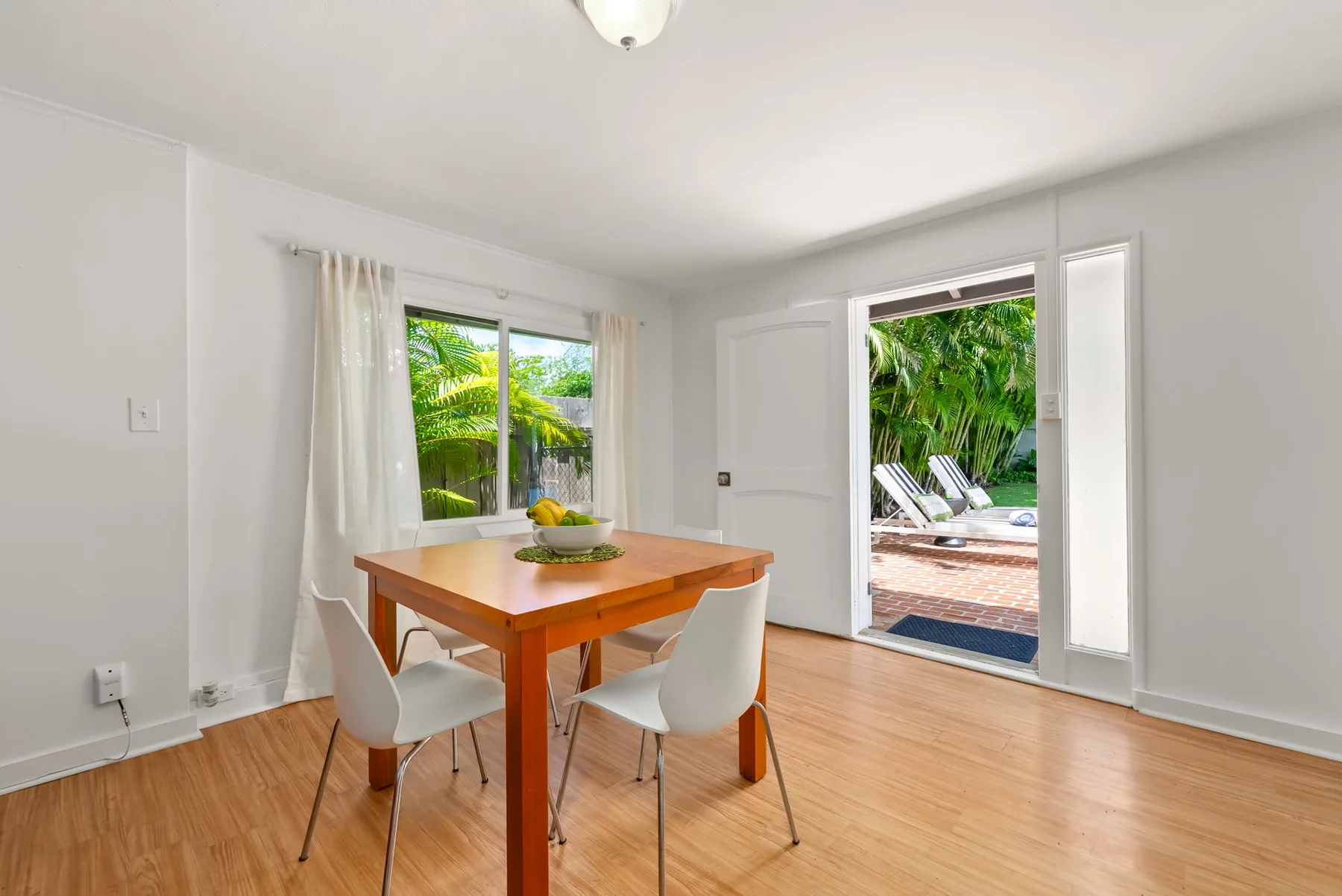 Comedor con una mesa de madera junto a ventanas y una puerta abierta al patio.