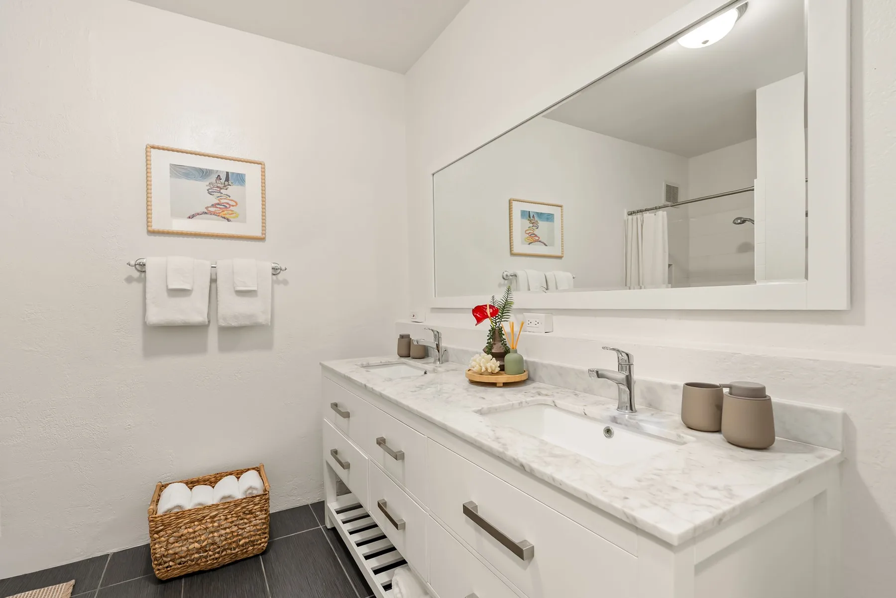 Un baño luminoso con un largo tocador, lavabo y un gran espejo.